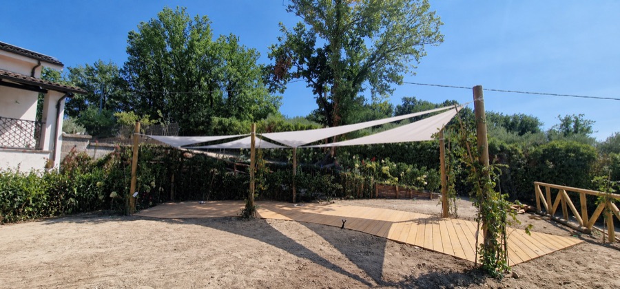 Vela tensile triangolare su dehor con pedana in legno