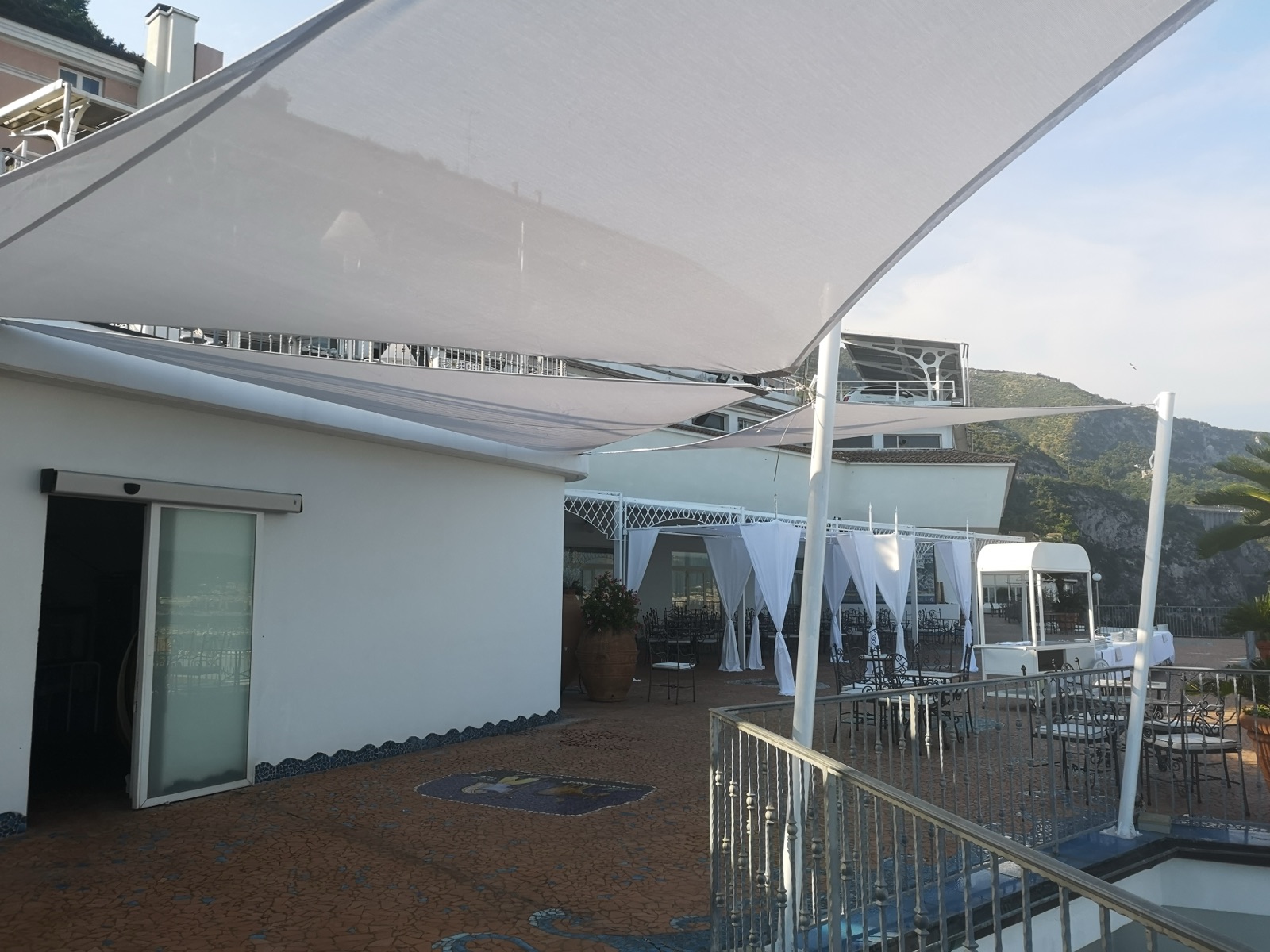 Vele tensili bianche su terrazza a bordo mare durante un evento